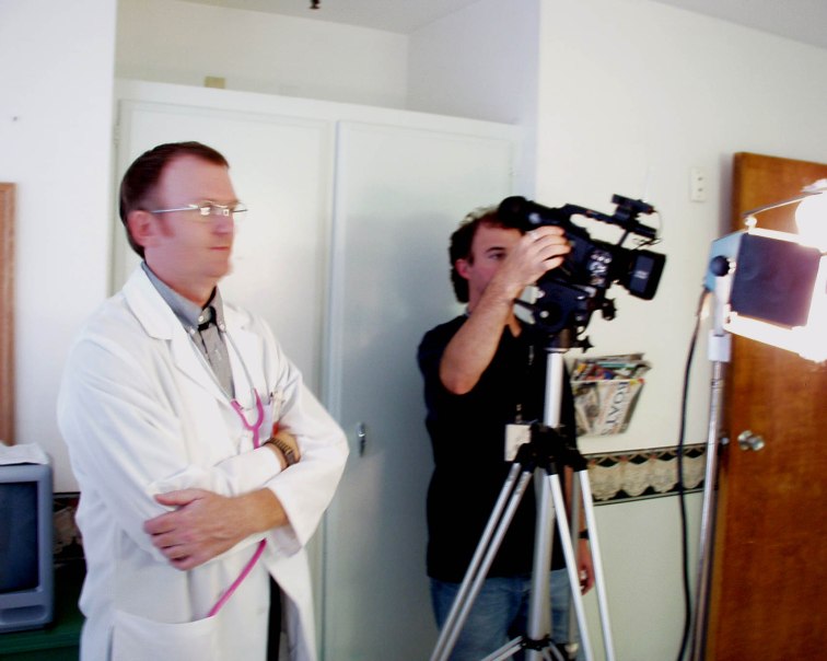 The Author, Daniel Wolfert, standing next to a camera man and dressed as a physician, preparing to act the part in a movie. 