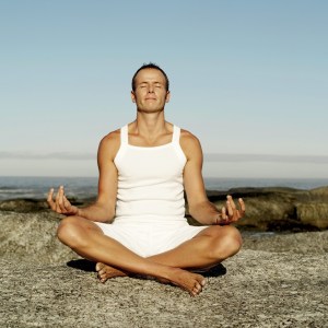 An image portraying a man meditating on a hilltop.