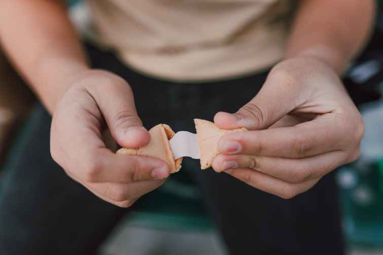 A close up shot of a man opening a fortune cookie. 