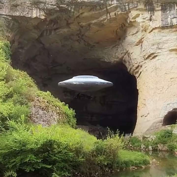 An image depicting a UFO emerging from a cave in a remote location.
