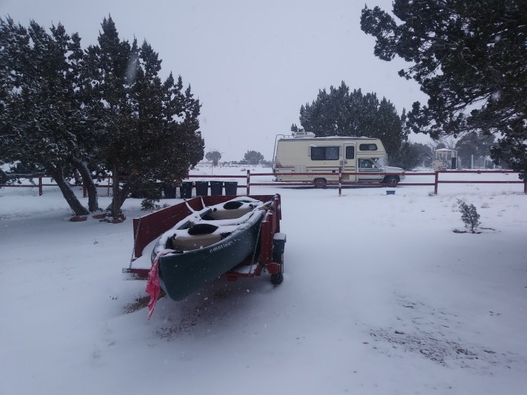 An image of a trailer parked in front of an RV in the snow.